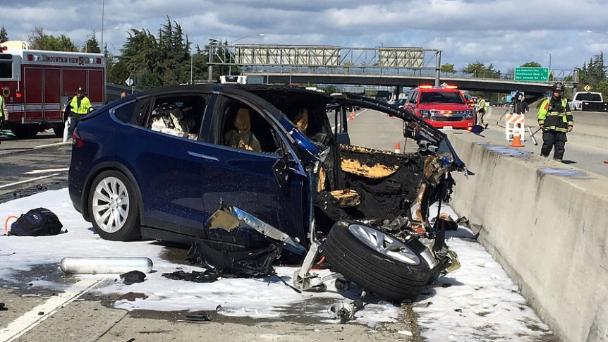 Rescue workers attend the scene where a Tesla Model X SUV crashed