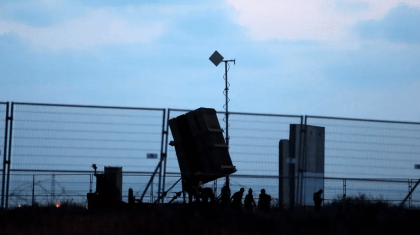 Israeli soldiers walk next to an Iron Dome anti-missile system