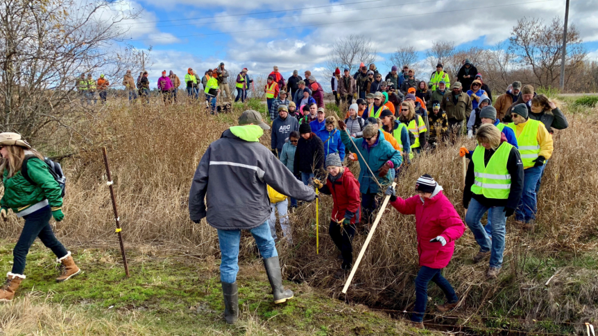 Volunteers cross a creek and barbed wire near Barron, Wis.,