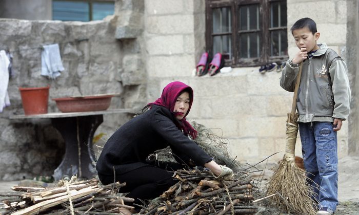 A woman farmer tieing a bunch of firewood as her son watches 