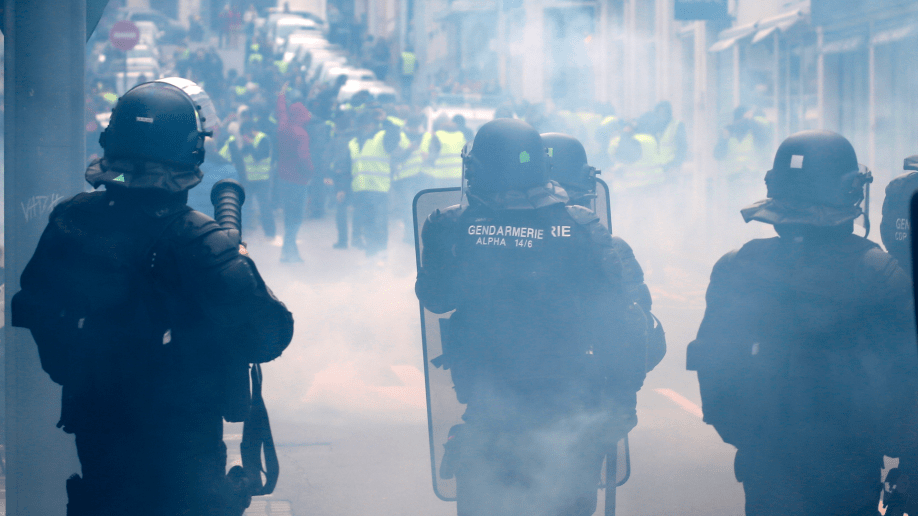 Demonstrators wearing yellow vests face riot police officers