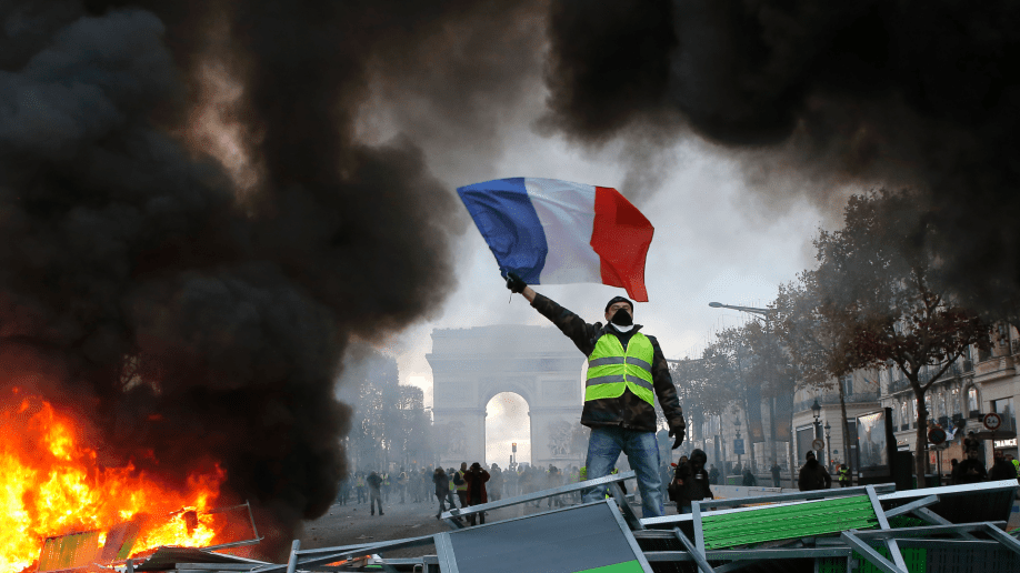 demonstrator waves the French flag on a burning barricade