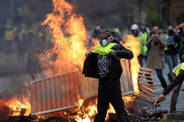 A demonstrator walks past a fire during a Gilets jaunes protest in Paris