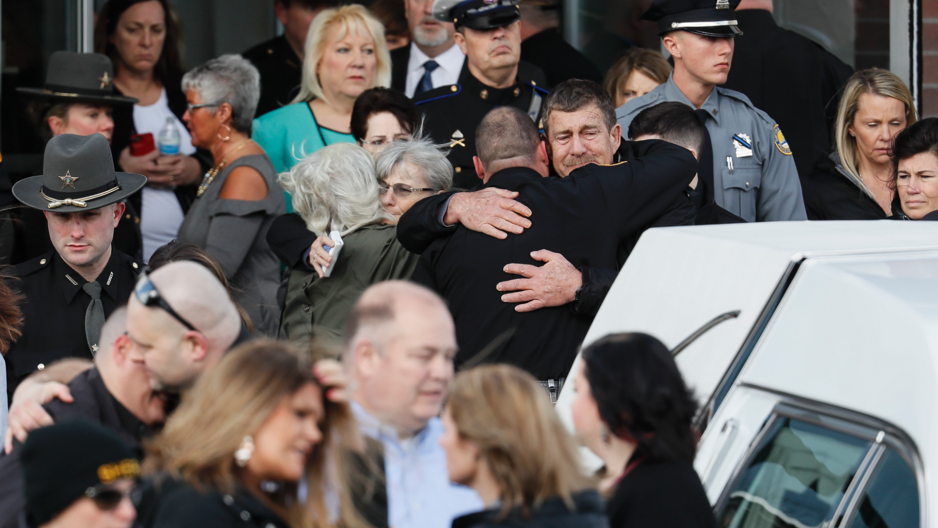 Officers and mourners react after the casket of Detective Bill Brewer,