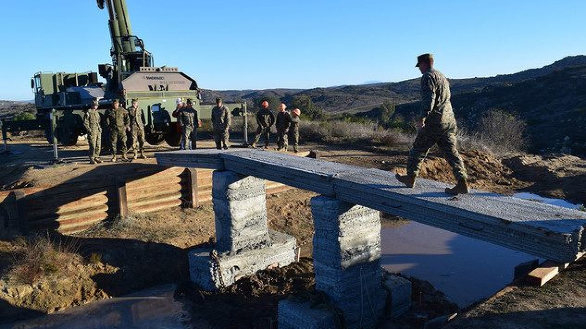 A Marine with 1st Marine Logistics Group walks across the 3D-printed concrete footbridge