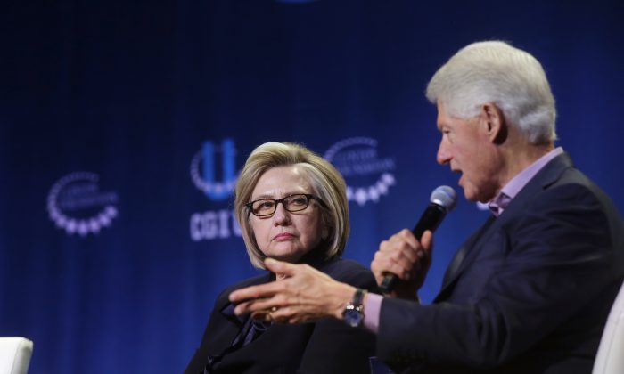 Former Secretary of State Hillary Clinton listens as former President Bill Clinton speaks