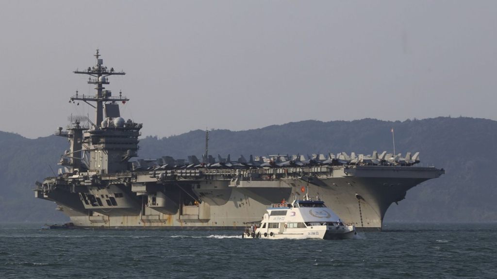 In this March 5, 2018, file photo, a Vietnamese passenger boat sails past U.S. aircraft carrier USS Carl Vinson