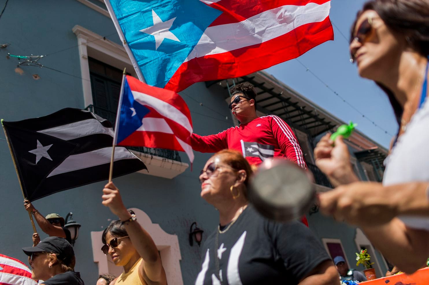 Demonstrators, some waving Puerto Rican national flags, gather in front of the governor’s mansion 