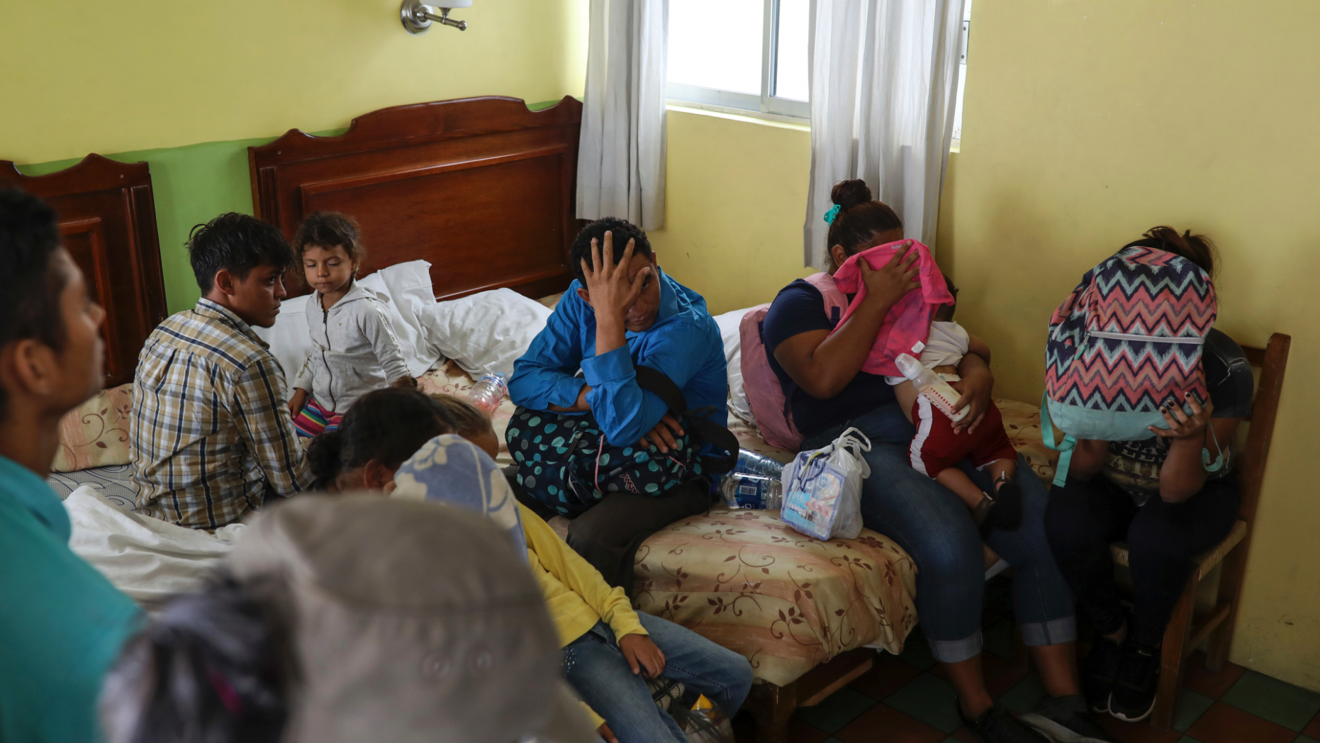 Central American migrants sit together inside a room at the Latino hotel during a raid by Mexican immigration agents