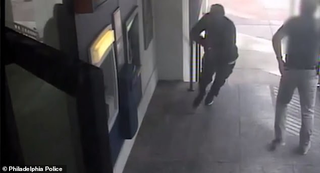 The men - clad in black hoodies and ski masks - then storm towards two Garda guards who are loading up the ATM.