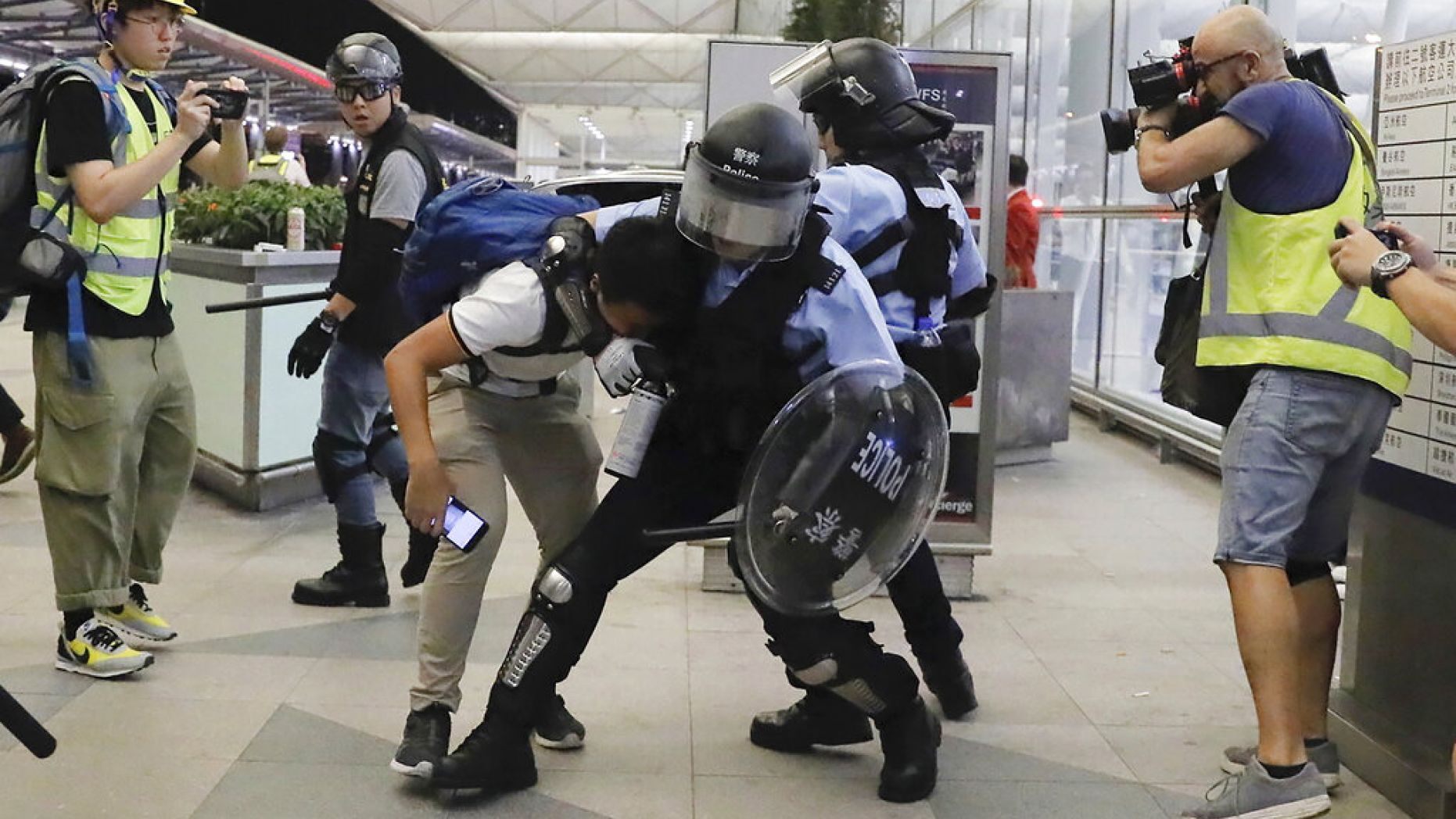 Policemen in riot gear arrest a protester during a demonstration at the airport in Hong Kong, Tuesday, Aug. 13, 2019.