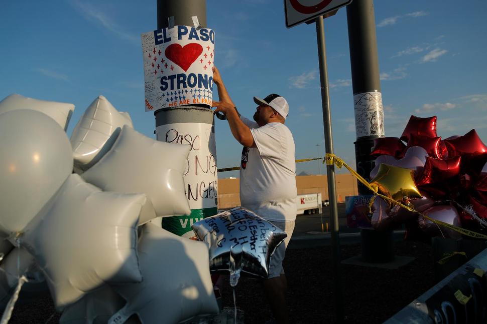 A man hangs up an "El Paso Strong" sign at a makeshift memorial at the scene of a mass shooting at a shopping complex, Tuesday, Aug. 6, 2019, in El Paso, Texas. 
