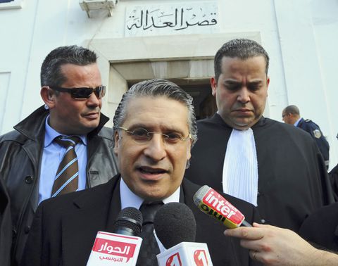 FILE - In this Jan.23 2012 file photo, the owner of the Tunisian private channel Nessma TV, Nabil Karoui, center, leaves the Tunis courthouse after attending his trial