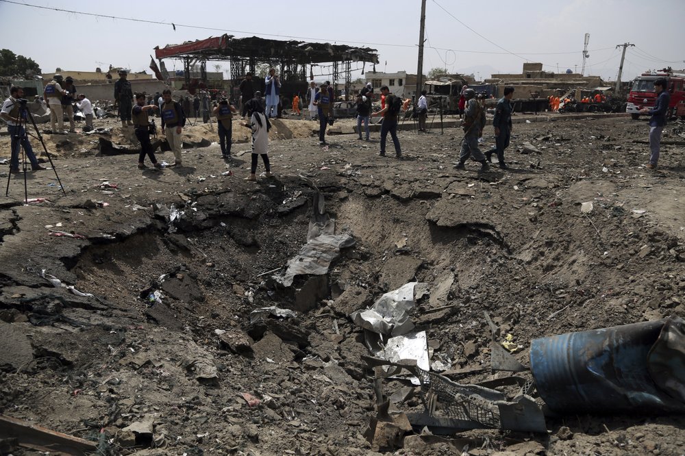 Journalists and security forces stand next to a crater caused by Monday's suicide bomb attack in Kabul, Afghanistan, Tuesday, Sept. 3, 2019. 