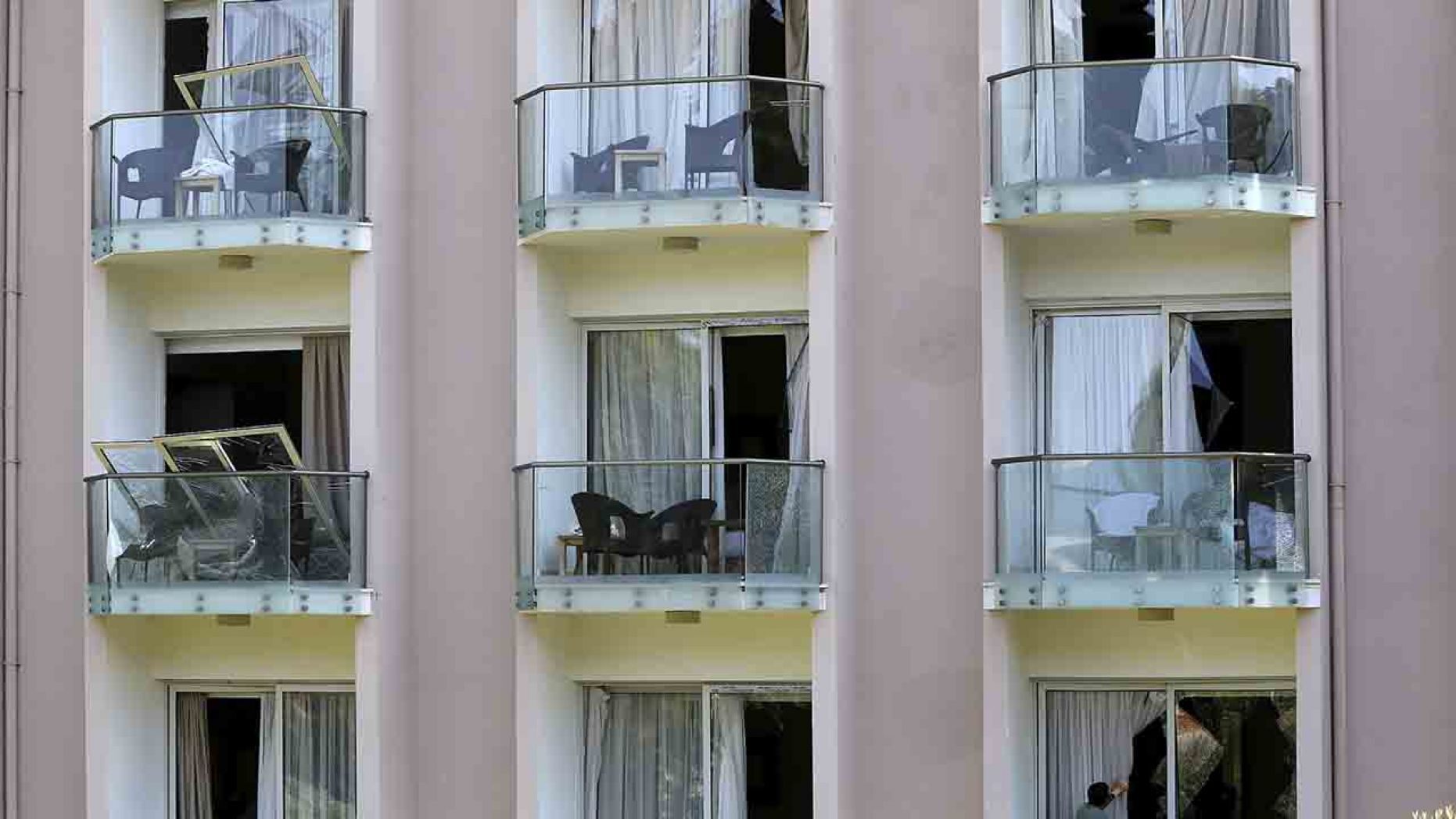 A worker on a balcony, below right, cleans up the debris after an explosion