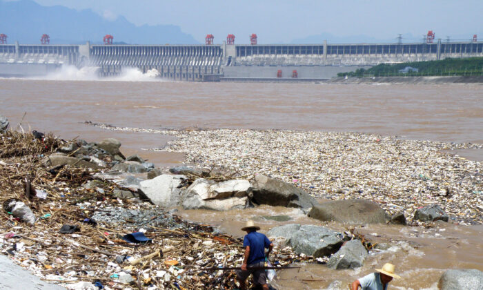 Two workers clean up trash along the bank of the Yangtze River near the Three Gorges Dam in Yichang, in central China's Hubei Province on Aug. 1, 2010.