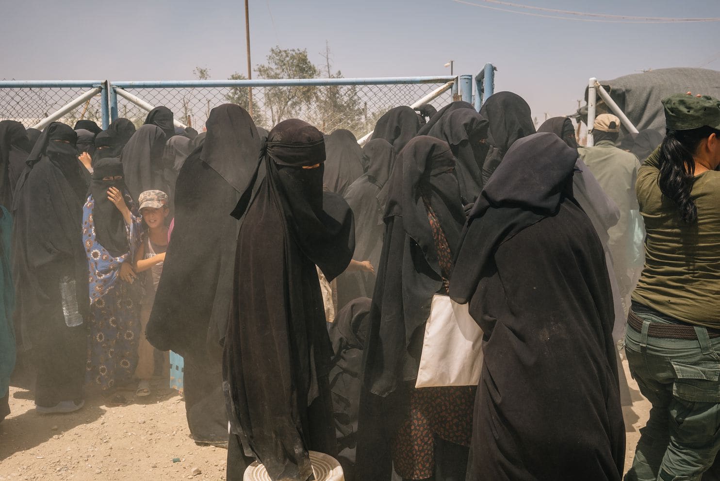 Women and children stand by a gate during a brief dust storm at the foreigners’ section of al-Hol camp.