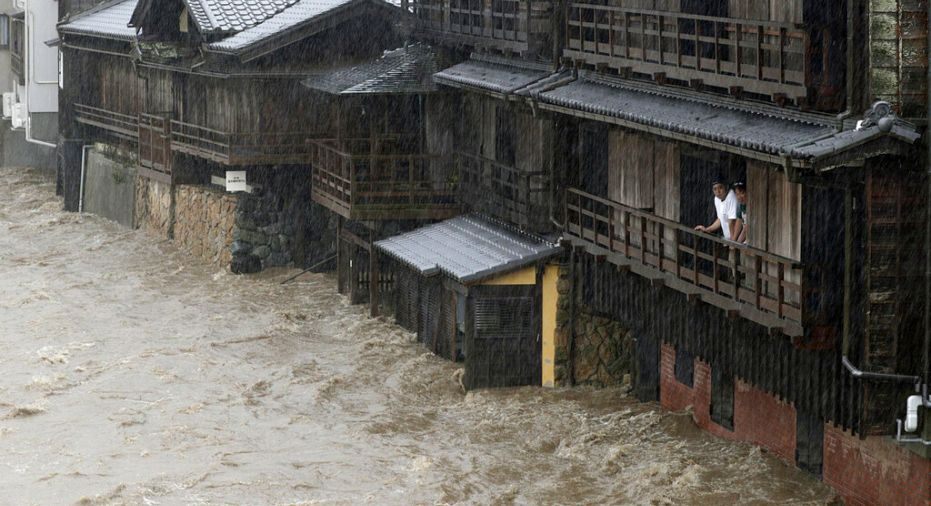 People watch the Isuzu River swollen by Typhoon Hagibis, in Ise, central Japan Saturday, Oct. 12, 2019.