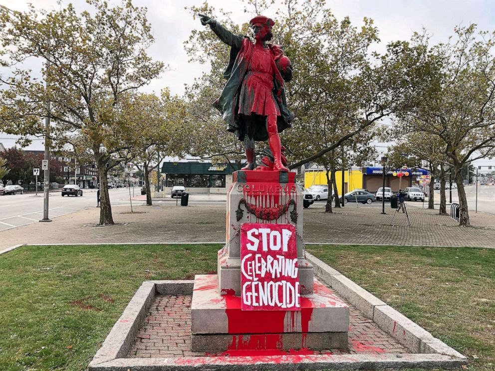 A sign reading "stop celebrating genocide" sits at the base of a statue of Christopher Columbus on Oct. 14, 2019, in Providence, R.I.