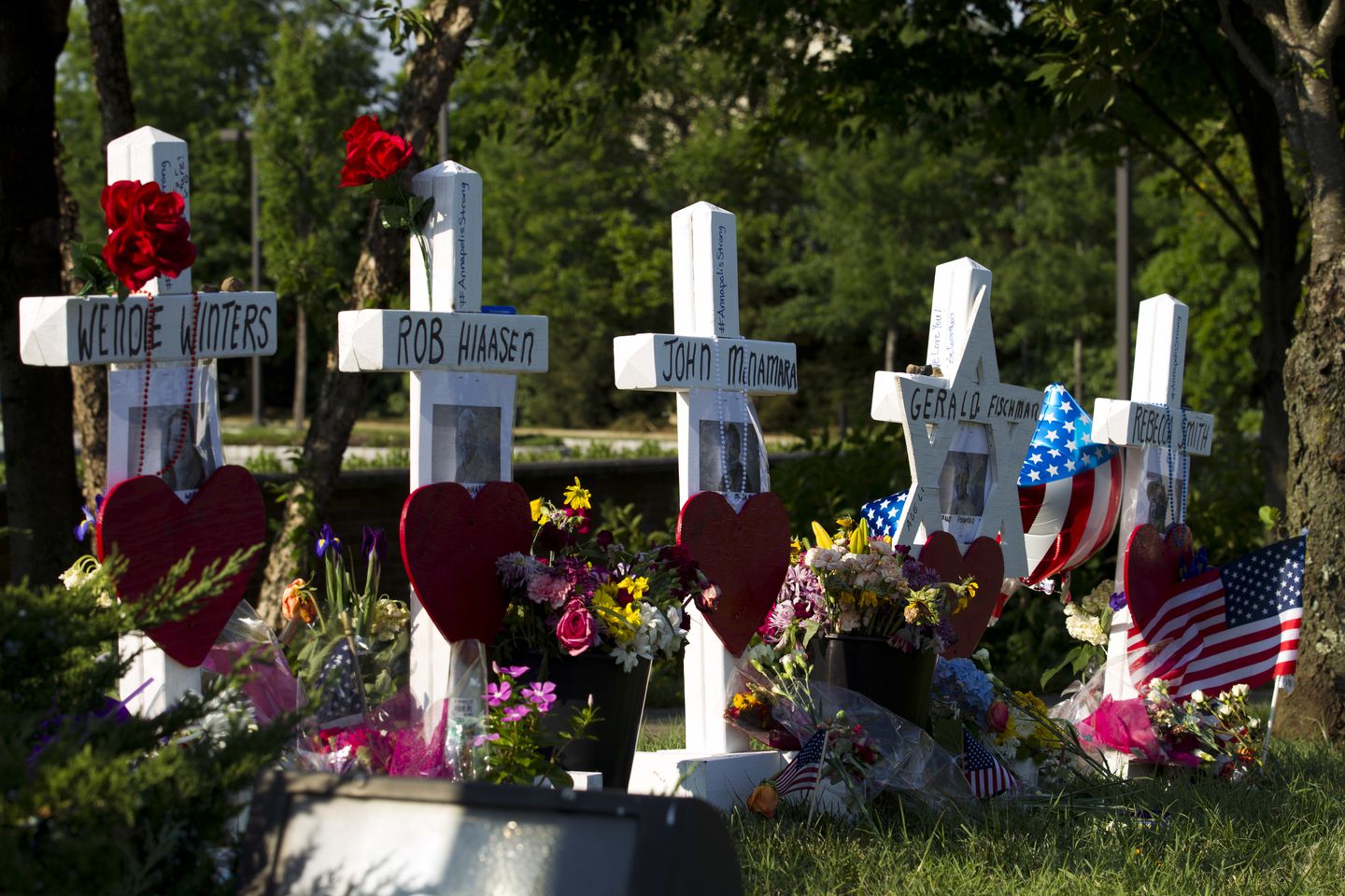 Markers representing the people killed in a newsroom shooting at a makeshift memorial at the scene outside the office building housing The Capital Gazette newspaper near Annapolis, Md. 