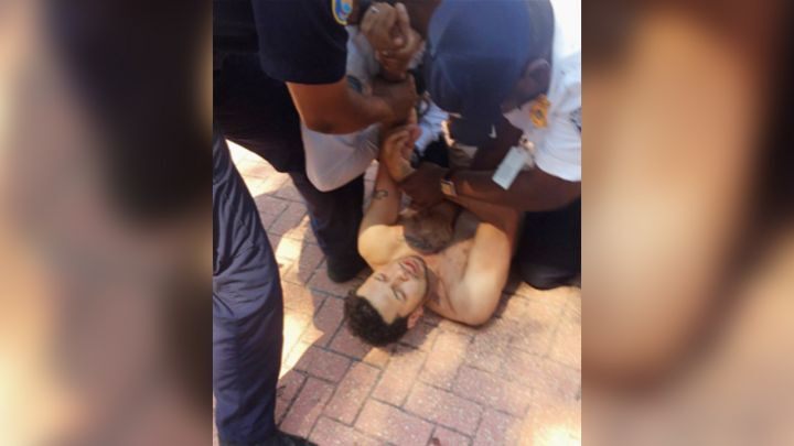 In this June 17, 2018, photo provided by the Mims family shows security guards at Six Flags America holding down Nicholaus Mims on the ground in Woodmore, Md.
