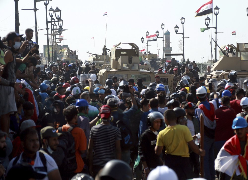 Iraqi Army soldiers try to prevent anti-government protesters from crossing the al- Shuhada (Martyrs) bridge in central Baghdad, Iraq, Wednesday, Nov. 6, 2019. Tens of thousands of people have taken to the streets in recent weeks in the capital, Baghdad, and across the Shiite south, demanding sweeping political change.