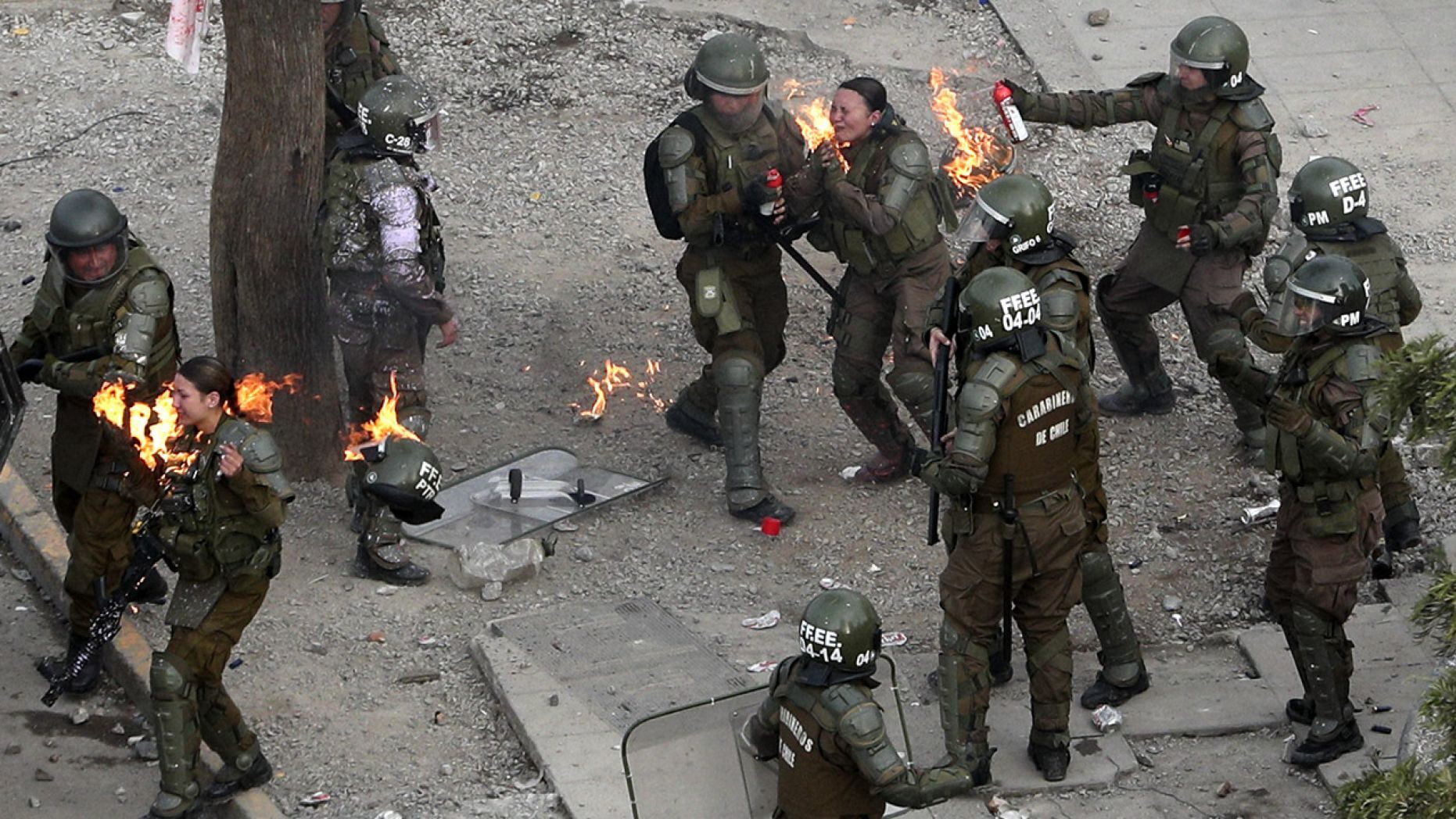 Police officers run to get assistance after being hit with a gasoline bomb thrown by protesters during an anti-government protest in Santiago, Chile, Monday, Nov. 4, 2019. 