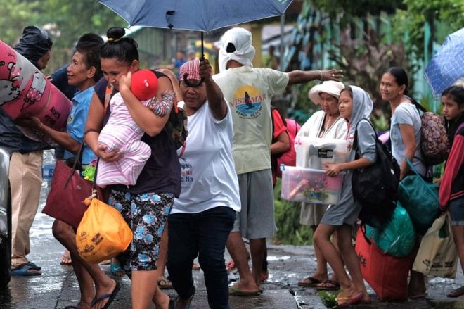 Villagers carry their belongings as they are evacuated in the eastern Philippines.
