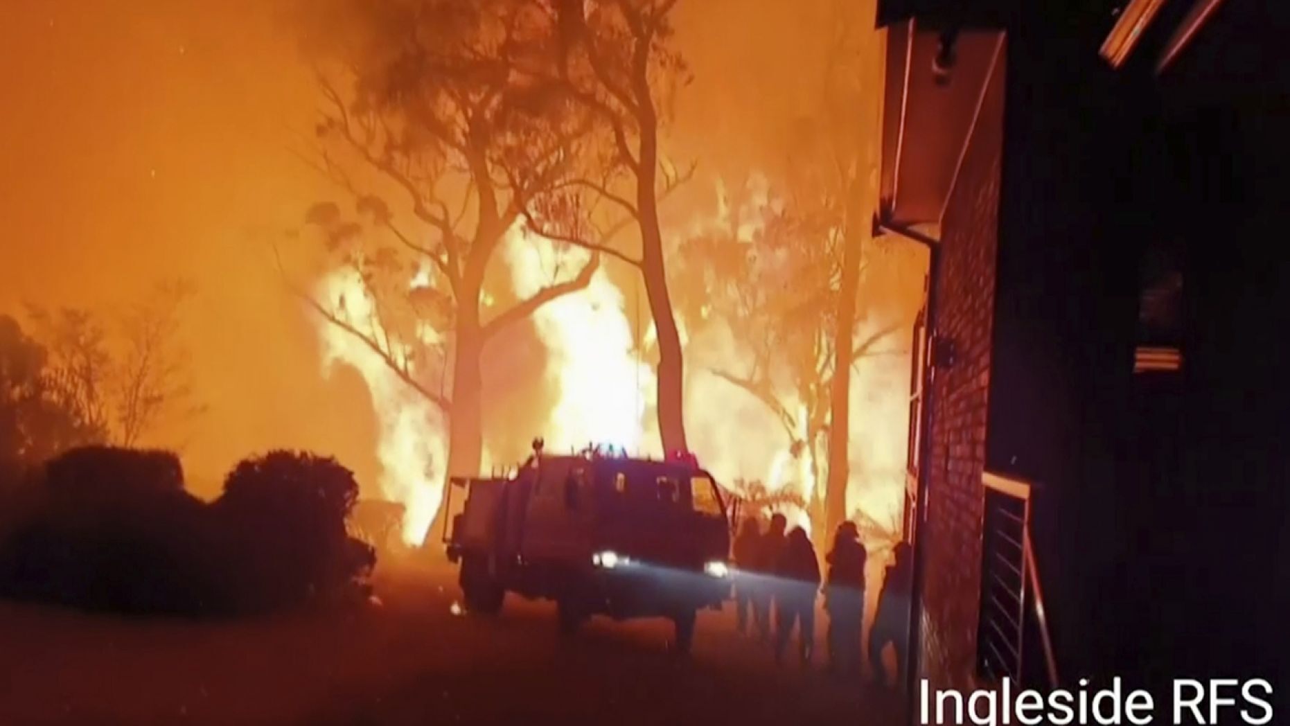 This image made from video taken on Dec. 22, 2019, and provided Dec. 25, 2019, by Ingleside Rural Fire Brigade, shows the wildfire behind an emergency vehicle near property on Hat Hill Road in Blackheath, New South Wales. 