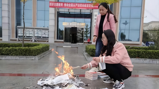 Two workers are seen burning books in front of the Zhenyuan county library in Qingyang City, Gansu Province, on Oct. 22, 2019.