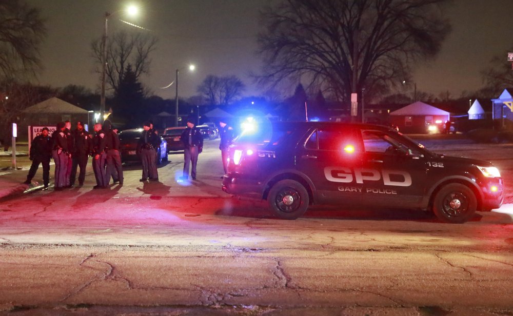 Gary and Indiana State Police officer stand at the entrance to the Westbrook Apartments where Gary police officers were wounded in a shooting incident Monday evening, Jan. 13, 2020 in Gary, Ind. One of the officers returned fire killing the suspect.