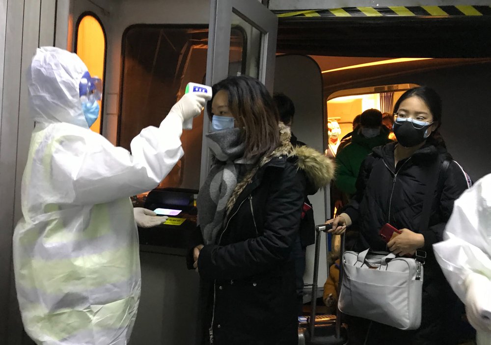 Health Officials in hazmat suits check body temperatures of passengers arriving from the city of Wuhan Wednesday, Jan. 22, 2020, at the airport in Beijing, China. Nearly two decades after the disastrously-handled SARS epidemic, China’s more-open response to a new virus signals its growing confidence and a greater awareness of the pitfalls of censorship, even while the government is as authoritarian as ever. 