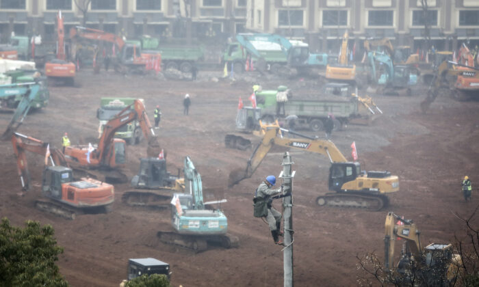 An electrician sets up wiring while workers drive excavators at the construction site of a new hospital designed to cope with the surge of 2019 Novel Coronavirus patients, in Wuhan, China on Jan. 24, 2020. (Getty Images)
