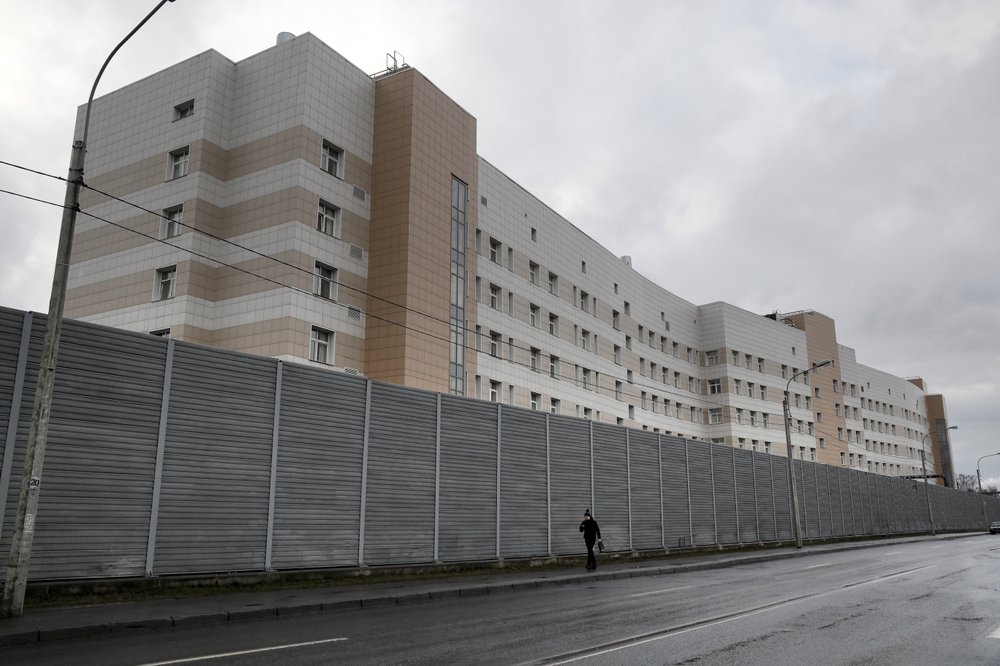 A man walks past a fence in front of the Botkin hospital in St. Petersburg, Russia, Wednesday, Feb. 12, 2020.