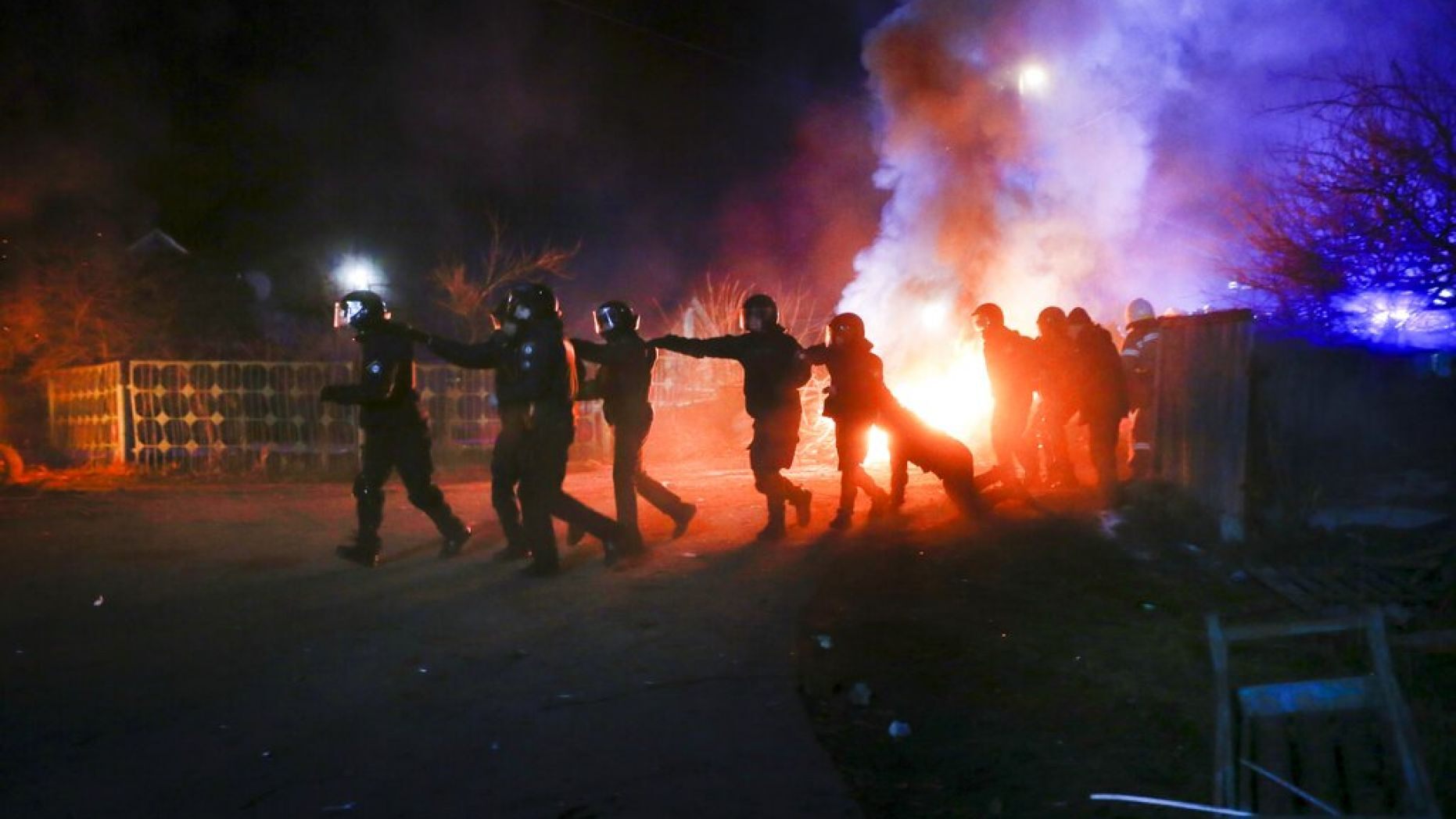 Ukrainian riot police run to push protesters, who planned to stop buses carrying passengers evacuated from the Chinese city of Wuhan,