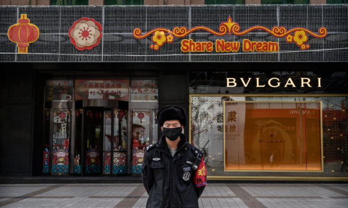 A Chinese security guard wears a protective mask as he stands on a commercial street in Beijing, China, on Feb. 18, 2020. 