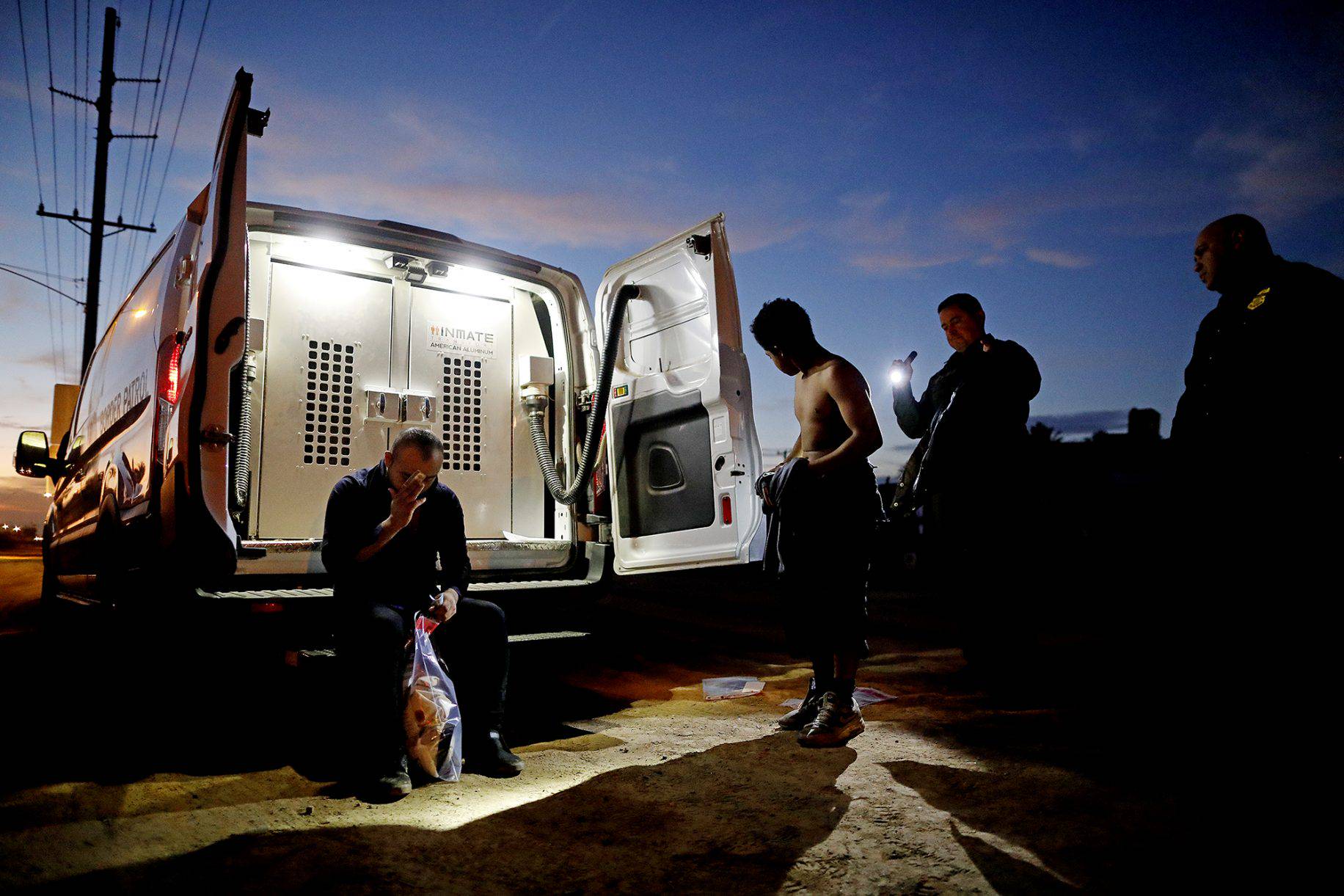 U.S. Border Patrol agents apprehend illegal immigrants, a Mexican, left, and a 15-year-old minor from Honduras, along the U.S.-Mexico border, Calexico and Mexicali, in Imperial, Calif.