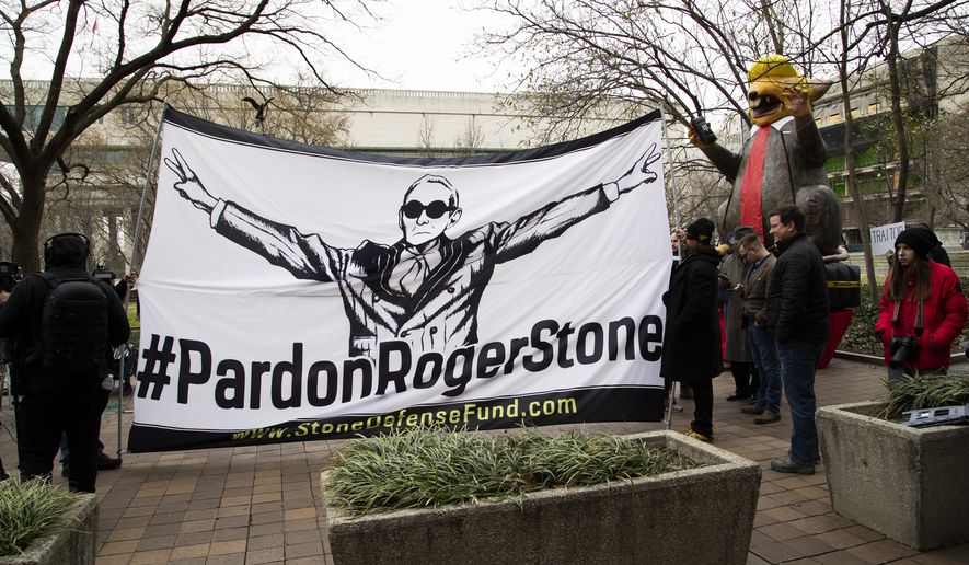 Supporters of Roger Stone with a banner that reads "#PardonRogerStone" wait outside federal court in Washington, Thursday, Feb. 20, 2020.