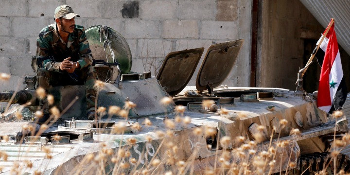 A Syrian army soldier smokes cigarette as he sits on a military vehicle in Khan Sheikhoun, Idlib, Syria,