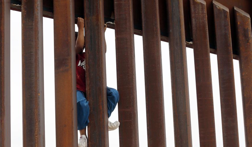 Children from Anapra, Mexico, climb a section of the new border wall recently built near Santa Teresa, N.M., Monday, April 9, 2018.