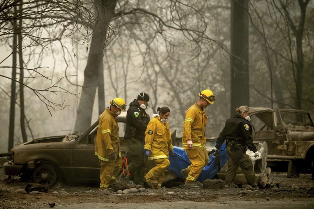In this Nov. 14, 2018, file photo, firefighters and deputies carry the body of a Camp Fire victim at the Holly Hills Mobile Estates in Paradise, Calif.