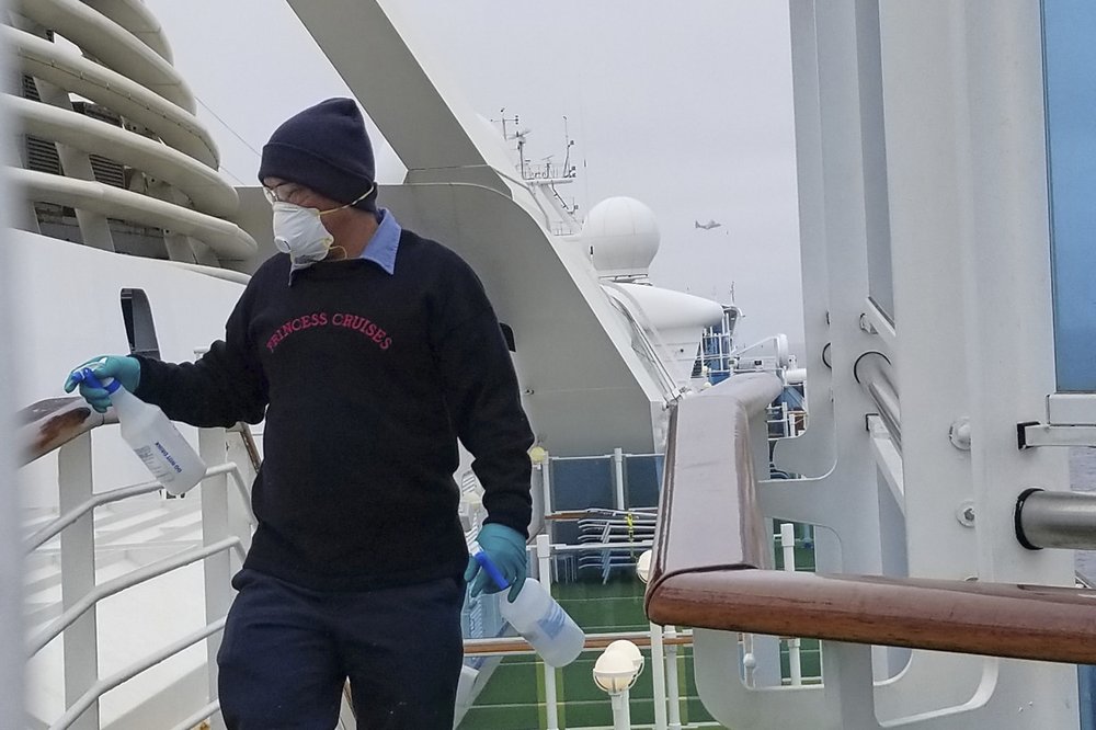 In this photo provided by Michele Smith, a cruise ship worker cleans a railing on the Grand Princess Thursday, March 5, 2020, off the California coast.