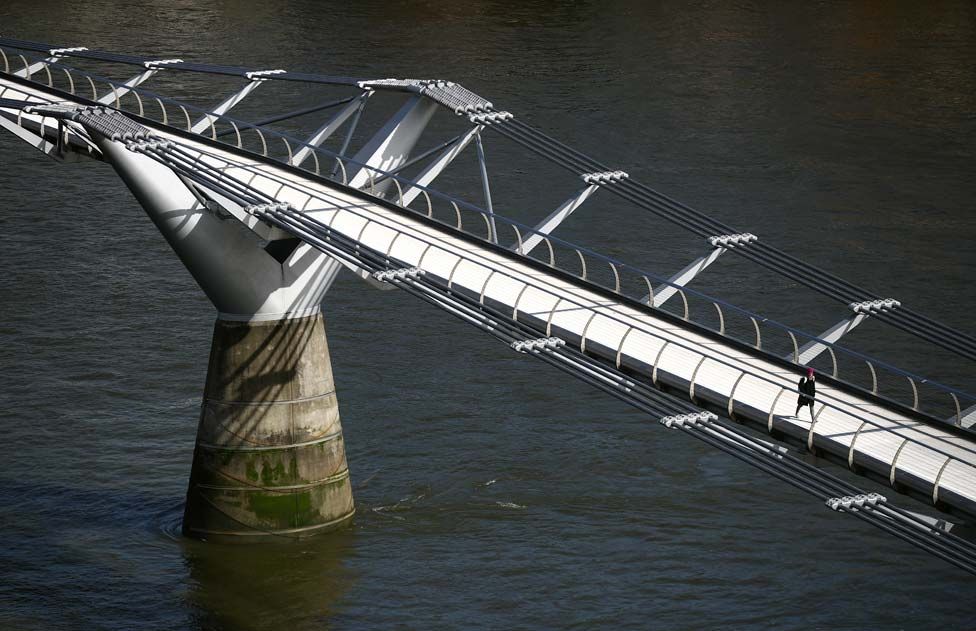 A woman walks across an empty Millennium Bridge during London's rush hour.