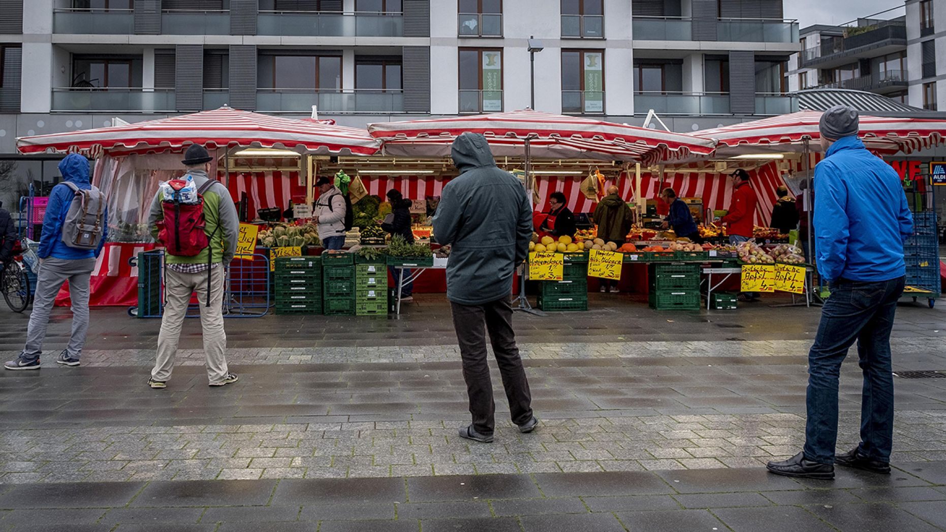 People keep distance as they queue on a small weekly market in Frankfurt, Germany