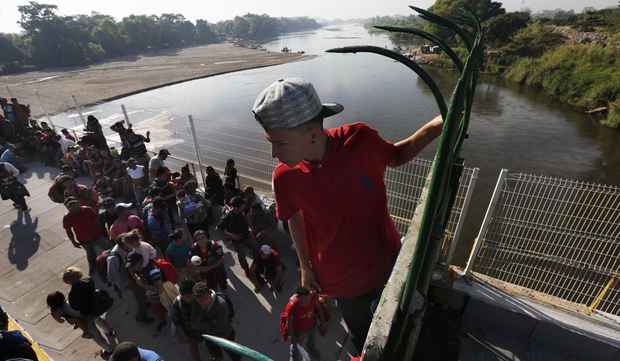 A migrant climbs the fence at the border crossing between Guatemala and Mexico in Tecun Uman, Guatemala, Saturday, Jan. 18, 2020. 