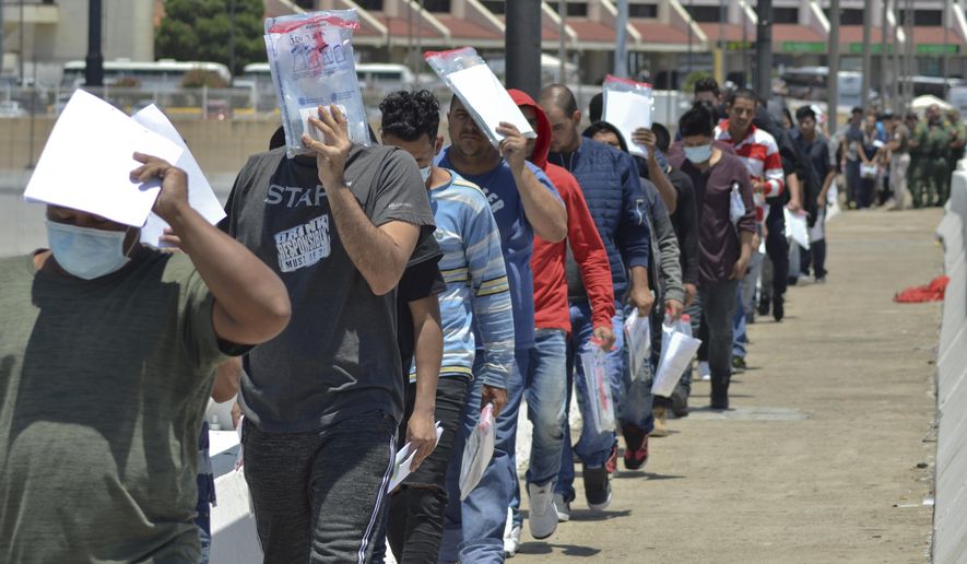 In this July 25, 2019, file photo, United States Border Patrol officers return a group of migrants back to the Mexico side of the border as Mexican immigration officials check the list, in Nuevo Laredo, Mexico.