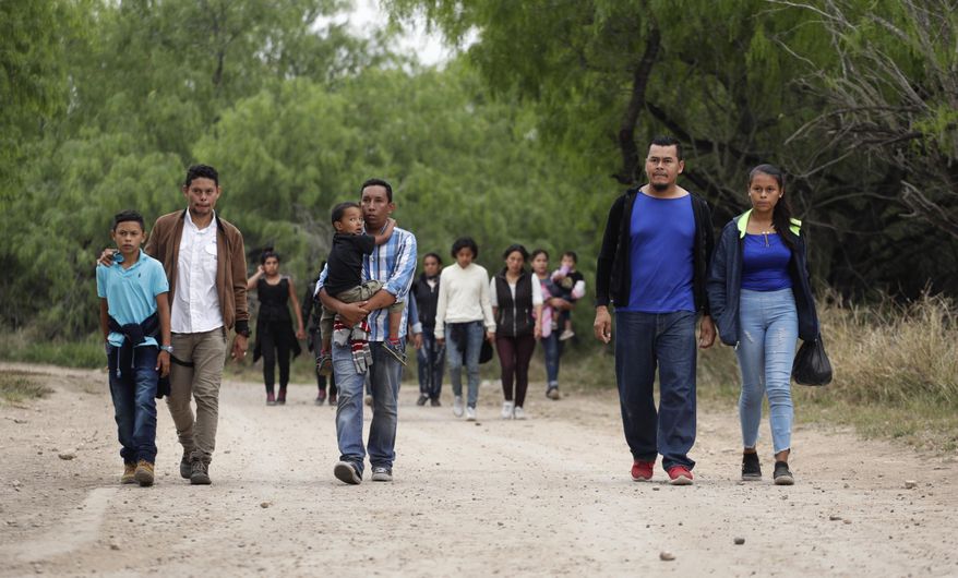 In this Thursday, March 14, 2019, photo, a group of migrant families walk from the Rio Grande, the river separating the U.S. and Mexico in Texas, near McAllen, Texas. 