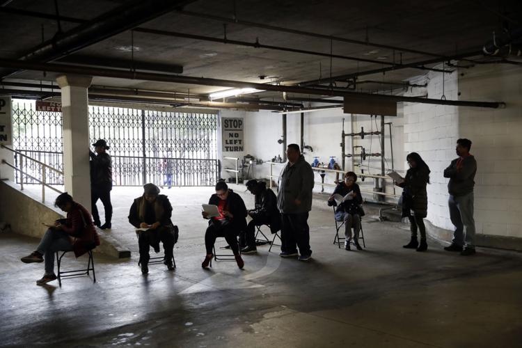 Unionized hospitality workers wait in line in a basement garage to apply for unemployment benefits at the Hospitality Training Academy Friday, March 13, 2020, in Los Angeles.