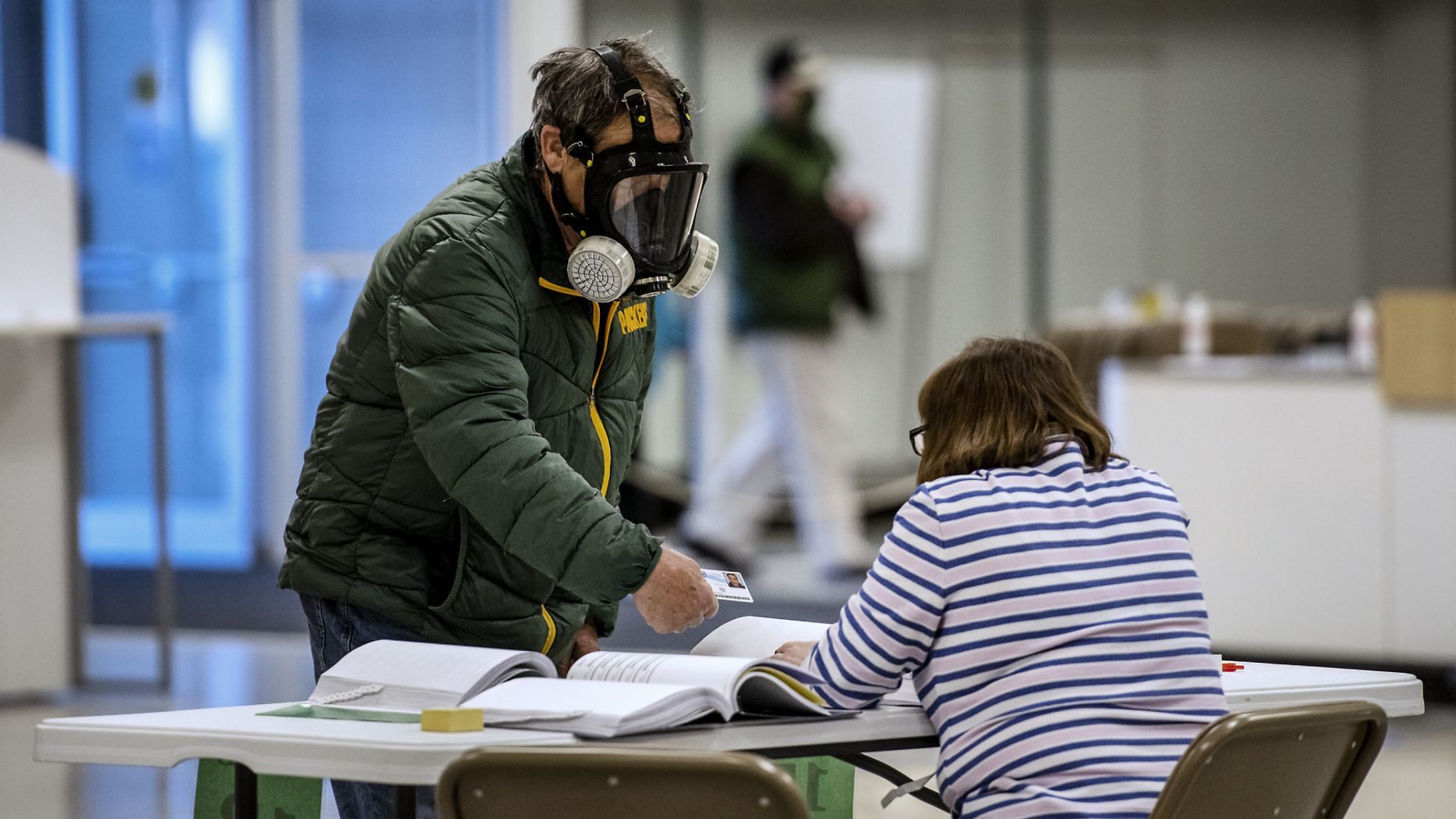 Robert Forrestal, left, wears a full face chemical shield to protect against the spread of coronavirus, as he votes Tuesday, April 7, 2020, 