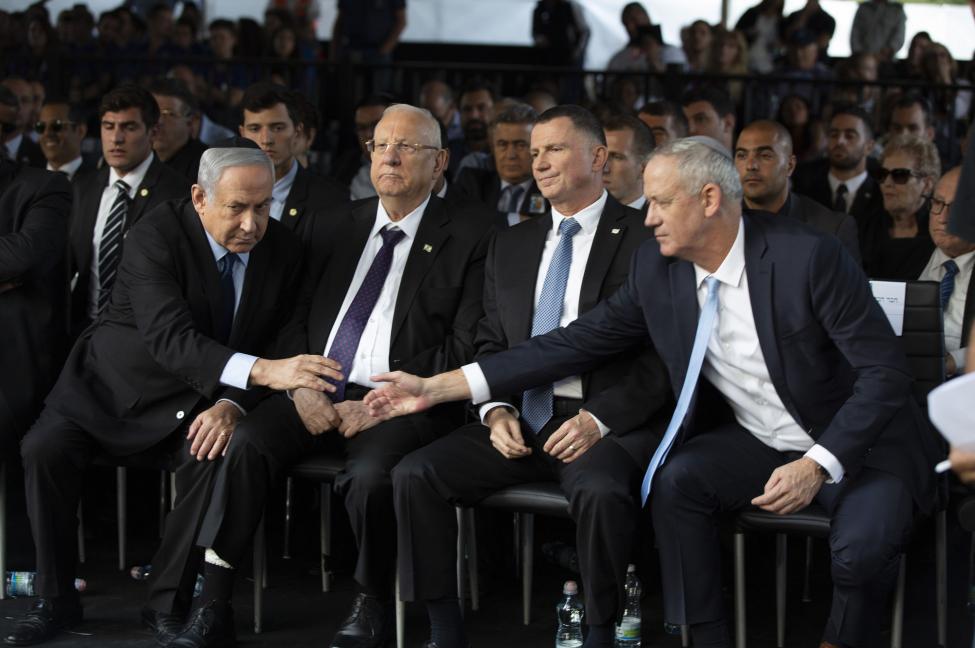 Blue and White party chief Benny Gantz (R) reaches out to shake hands with Israeli Prime Minister Benjamin Netanyahu